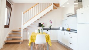 A modern kitchen with white cabinets, a wooden staircase, and a dining area with a yellow tablecloth. - Pico El Hayal - Apar located in a rural setting with 2 bedrooms, kitchen, living room and bathroom (Ampuero)
