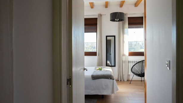 A bedroom with a bed, a chair, a window with curtains, and a view of the outdoors. - Pico El Hayal - Apar located in a rural setting with 2 bedrooms, kitchen, living room and bathroom (Ampuero)