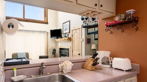 A kitchen with a sink, a toaster, a coffee maker, and a knife block. - Charming Studio + Loft Condo | Walk to Gondola | Pool, Hot Tubs and Views! (Steamboat Springs)