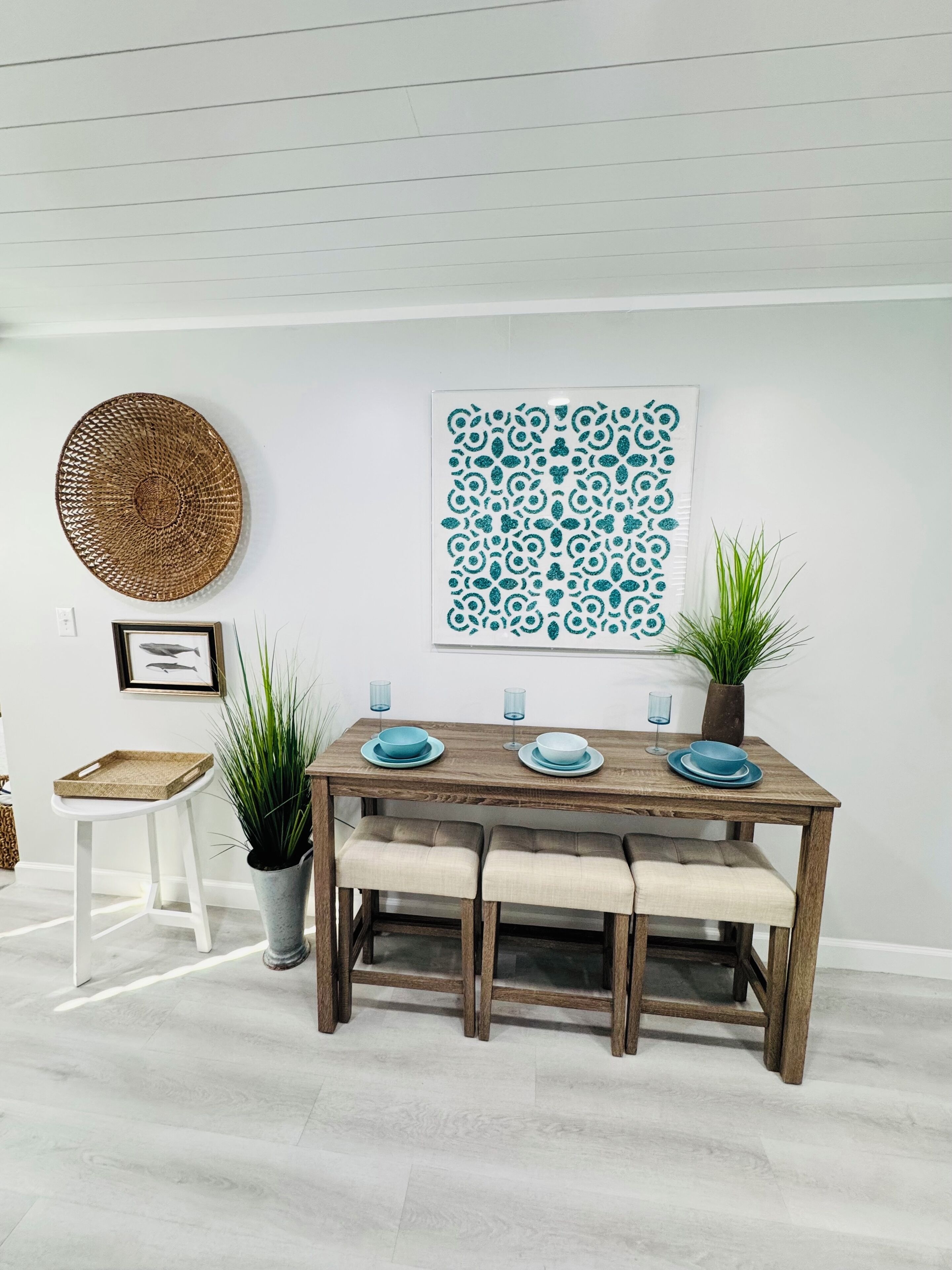 Un coin repas avec une table en bois, des assiettes bleues et une décoration murale tissée.