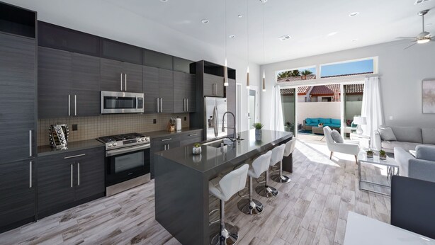A modern kitchen with dark cabinetry, stainless steel appliances, and a central island with bar stools. - Modern Escape, La Quinta Cove #259116, 4 BR (La Quinta)