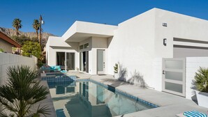 A modern house with a swimming pool, a garage, and a patio area with lounge chairs. - Modern Escape, La Quinta Cove #259116, 4 BR (La Quinta)