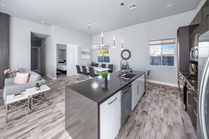 A modern kitchen with a central island, stainless steel appliances, and a dining area with a white table and chairs. - Modern Escape, La Quinta Cove #259116, 4 BR (La Quinta)