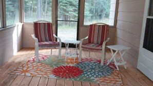 A cozy room with a wooden floor, two striped chairs, a small table, and a colorful rug. - GUEST CABIN IN THE WOODS (Bigfork)