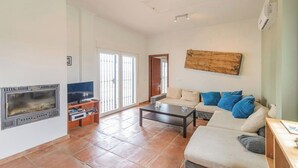 Uma sala de estar com lareira, sofá, mesa de centro e televisão.