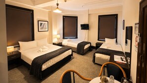 A hotel room with two beds, a TV, a desk, and a chair. - The Occidental Hotel (Sydney)