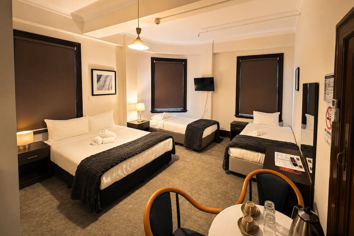 Une chambre d’hôtel avec deux lits, une télévision, un bureau et une chaise.