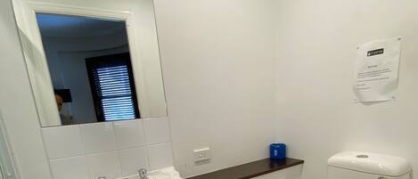 Un baño con lavamanos, espejo e inodoro blancos.
