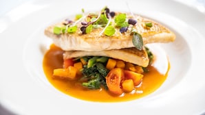 A plate of food with a fish fillet, vegetables, and a sauce. - The Occidental Hotel (Sydney)
