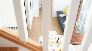 A view from a balcony overlooking a dining area with a table set for two, a sofa with cushions, and a wooden floor. - Pico Negro- apartment with two bedrooms, living room, kitchen and bathroom (Ampuero)