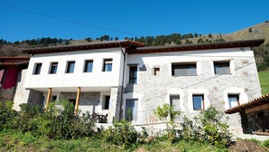 A two-story building with a stone facade and multiple windows. - Pico Negro- apartment with two bedrooms, living room, kitchen and bathroom (Ampuero)