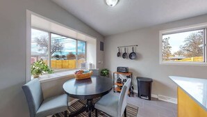 Une cuisine compacte avec une table ronde, des chaises, une petite poubelle et une fenêtre donnant sur l’extérieur.
