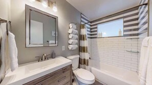 A modern bathroom with a large mirror, a toilet, a bathtub, and a shower area. - Charming Family Home in Lovely Littleton (Littleton)