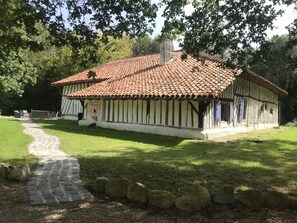 A traditional half-timbered house with a tiled roof, a stone pathway, and a grassy lawn. - traditional Landes house 16 people spa, swimming pool, billiards (Cachen)