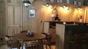 A wooden-paneled dining area with a round table and chairs, a kitchen with wooden cabinets, and pendant lighting. - Northwoods Best @  Amazing Grace Retreat Fantastic fishing, Awesome Relaxation! (Sayner)