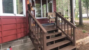 A wooden staircase leading to a porch with a wicker chair and a small table. - Northwoods Best @  Amazing Grace Retreat Fantastic fishing, Awesome Relaxation! (Sayner)