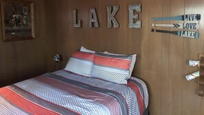 A bedroom with a bed, a wall-mounted sign reading "LAKE," and a sign with "LIVE LOVE LAKE." - Northwoods Best @  Amazing Grace Retreat Fantastic fishing, Awesome Relaxation! (Sayner)