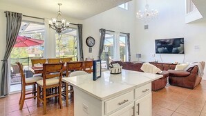 A spacious living area with a dining table, chairs, a sofa, and a TV. - Gathering Resort Pool/Spa Home-Mins away to the PARKS (Kissimmee)