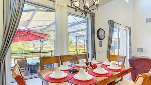 A dining area with a wooden table set for six, surrounded by chairs. - Gathering Resort Pool/Spa Home-Mins away to the PARKS (Kissimmee)