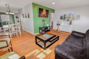 A living room with a leather sofa, a coffee table, and a dining area with chairs and a table. - Family Home with Large Yard & Golf Theme Near Rail (Denver)