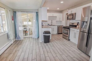 A modern kitchen with white cabinets, stainless steel appliances, and a tiled backsplash.