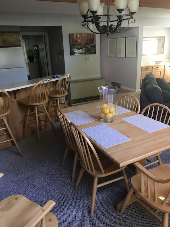 Un coin repas avec une table en bois, des chaises et un lustre.
