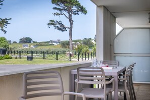 Una veranda esterna con tavolo e sedie, affacciata su un'area verde con alberi e una recinzione.