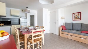 Ett kompakt bostadsutrymme med en matplats, ett litet kök och en soffa.