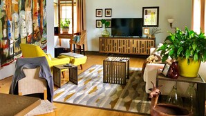Ein Wohnzimmer mit einem großen Gemälde, einem Fernseher und einem Blumentopf.
