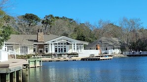 Uma pousada à beira do lago com um píer, um deck coberto e um edifício grande com várias janelas.