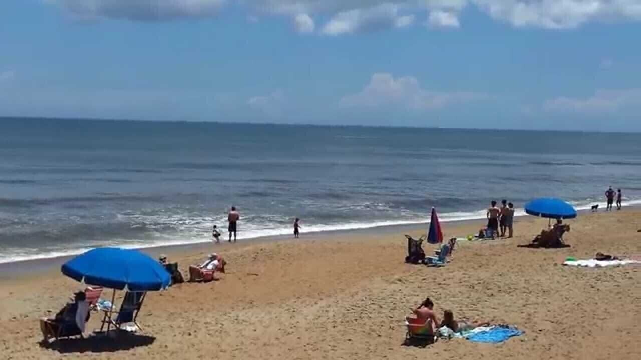 Una playa con gente tomando el sol y nadando.