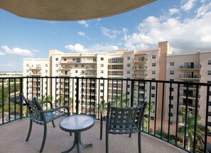 A balcony with two chairs and a table, overlooking a residential building complex.