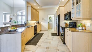 A modern kitchen with wooden cabinets, granite countertops, and stainless steel appliances. - Spacious Oasis w/ Lagoon Pool & Spa in Cape Coral! (Cape Coral)
