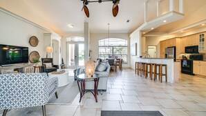 A spacious living area with a large TV, comfortable seating, and a kitchen with modern appliances. - Spacious Oasis w/ Lagoon Pool & Spa in Cape Coral! (Cape Coral)