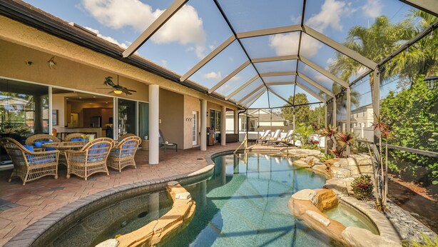 A pool area with a covered patio, lounge chairs, and a restaurant view. - Spacious Oasis w/ Lagoon Pool & Spa in Cape Coral! (Cape Coral)