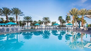 A clear blue pool surrounded by palm trees and lounge chairs.