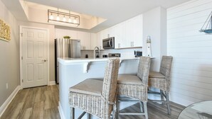 Una cocina moderna con armarios blancos, electrodomésticos de acero inoxidable y una isla integrada con taburetes de bar.