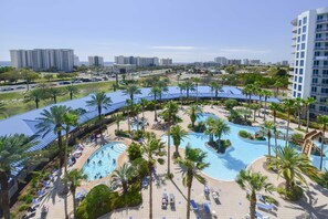 Een resort met een groot zwembad, palmbomen en uitzicht op de stadshemel.