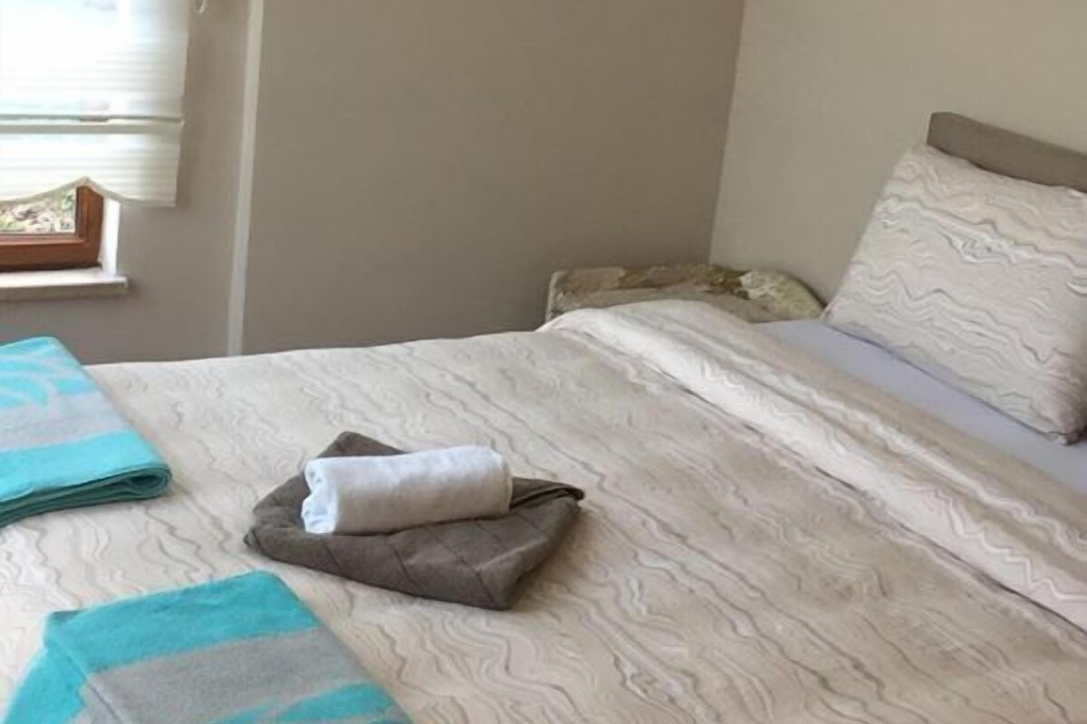 Un lit bien fait, avec une couvre-lit à motifs et deux serviettes pliées.
