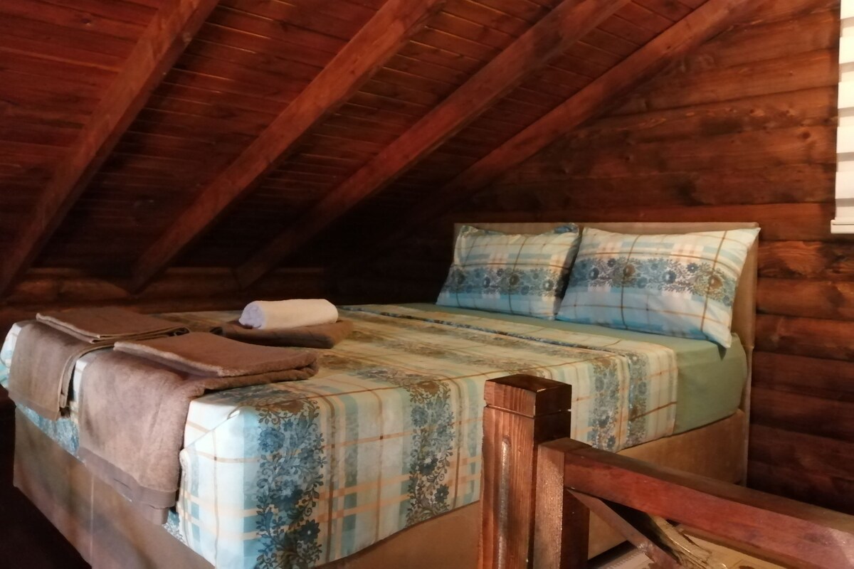 Une pièce dans un chalet en bois, avec un lit, des oreillers et une couverture.
