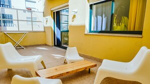 A yellow-walled room with white plastic chairs and a wooden table. - Help Yourself Hostels - Restelo (Lisbon)