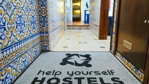 A hallway with patterned tiles leading to a room. A sign on the floor reads "help yourself HOSTELS." - Help Yourself Hostels - Restelo (Lisbon)