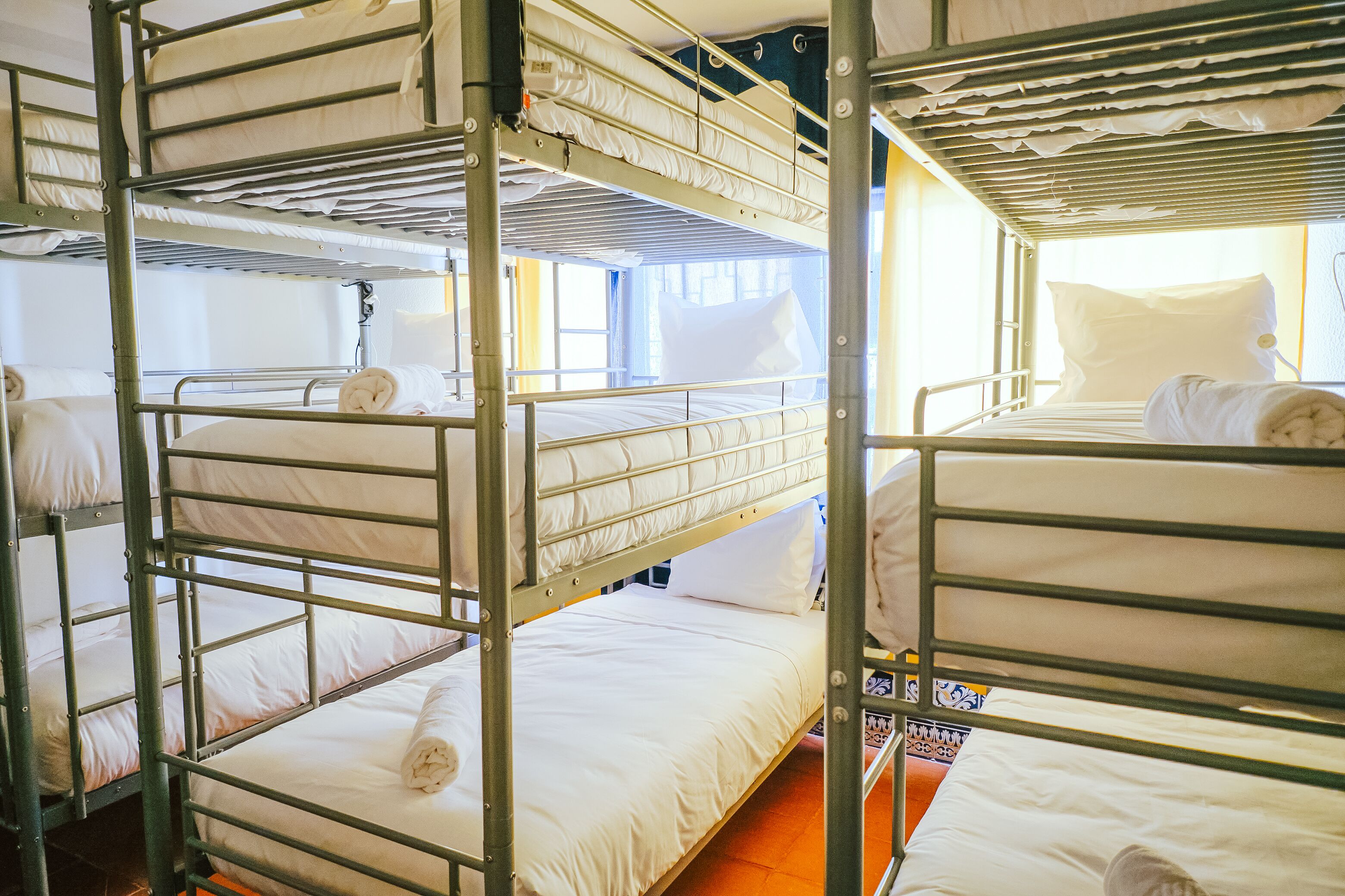 A bunk bed room with metal railings and white bedding.
