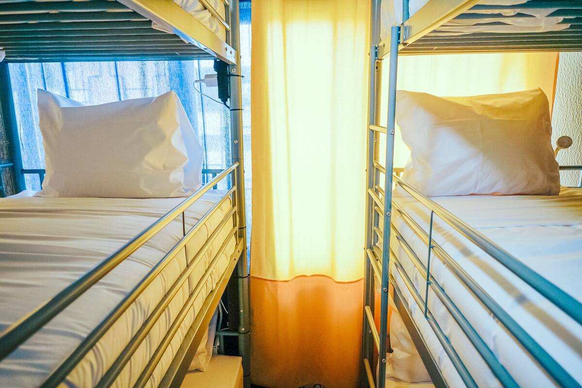 A bunk bed room with metal railings and a curtain divider.