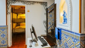 A room with a computer setup, a bed, and a decorative wall with a statue. - Help Yourself Hostels - Restelo (Lisbon)