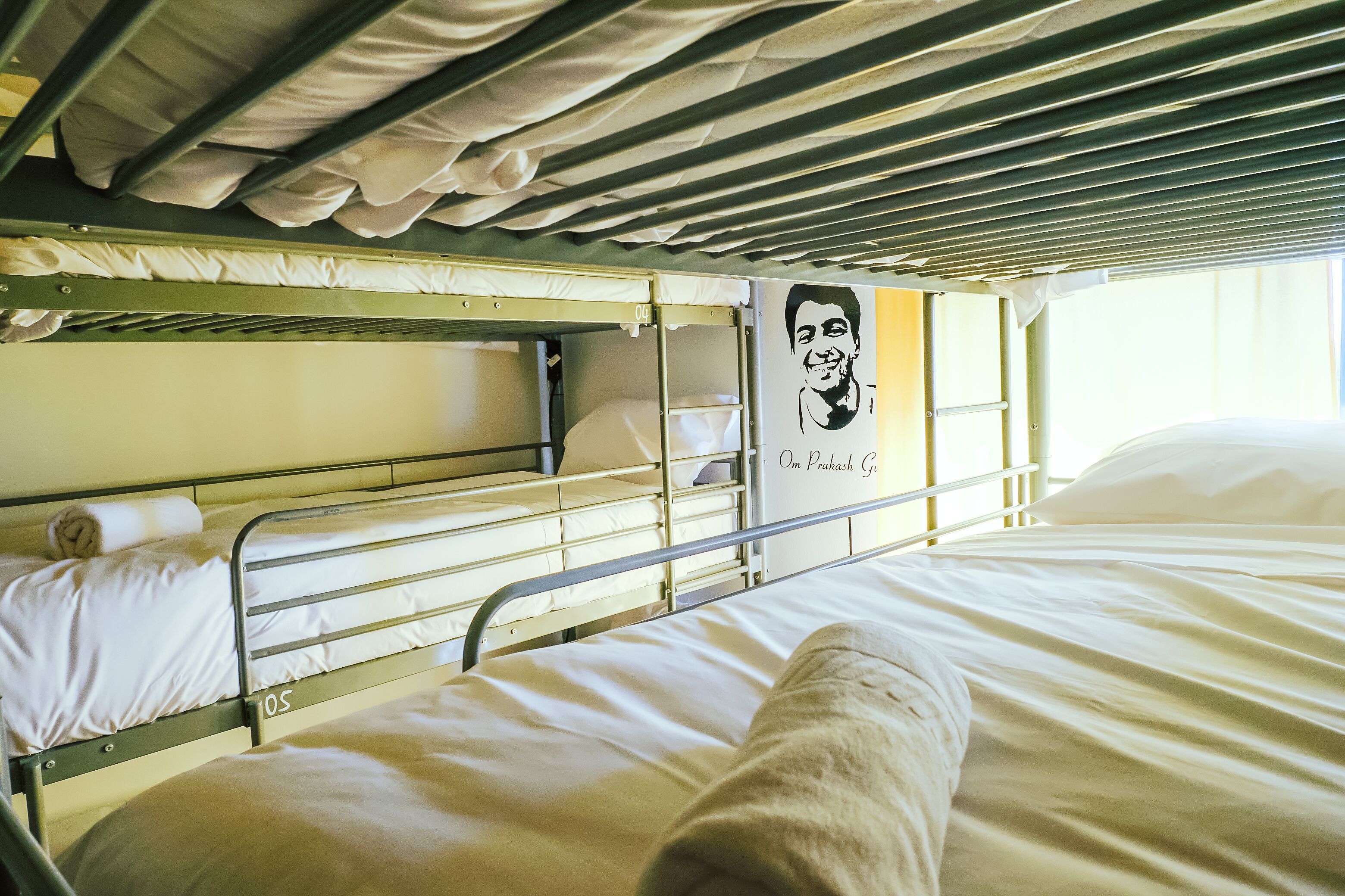 A bunk bed with white bedding and a poster on the wall.