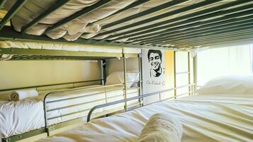 A bunk bed with white bedding and a poster on the wall.