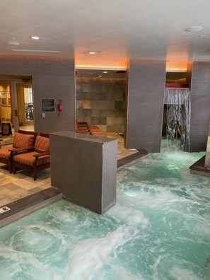 A spa area with a hot tub, seating, and a waterfall feature.