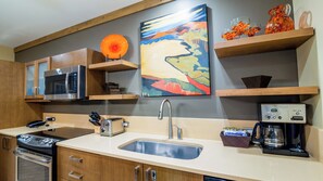A modern kitchen with a microwave, toaster, coffee maker, and a sink.