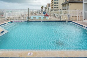 A swimming pool with a 'No Diving' sign, surrounded by a white fence, and a lifeguard tower in the background.
